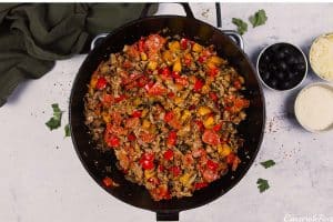 combining ingredients in a casserole dish to make supreme pizza gnocchi