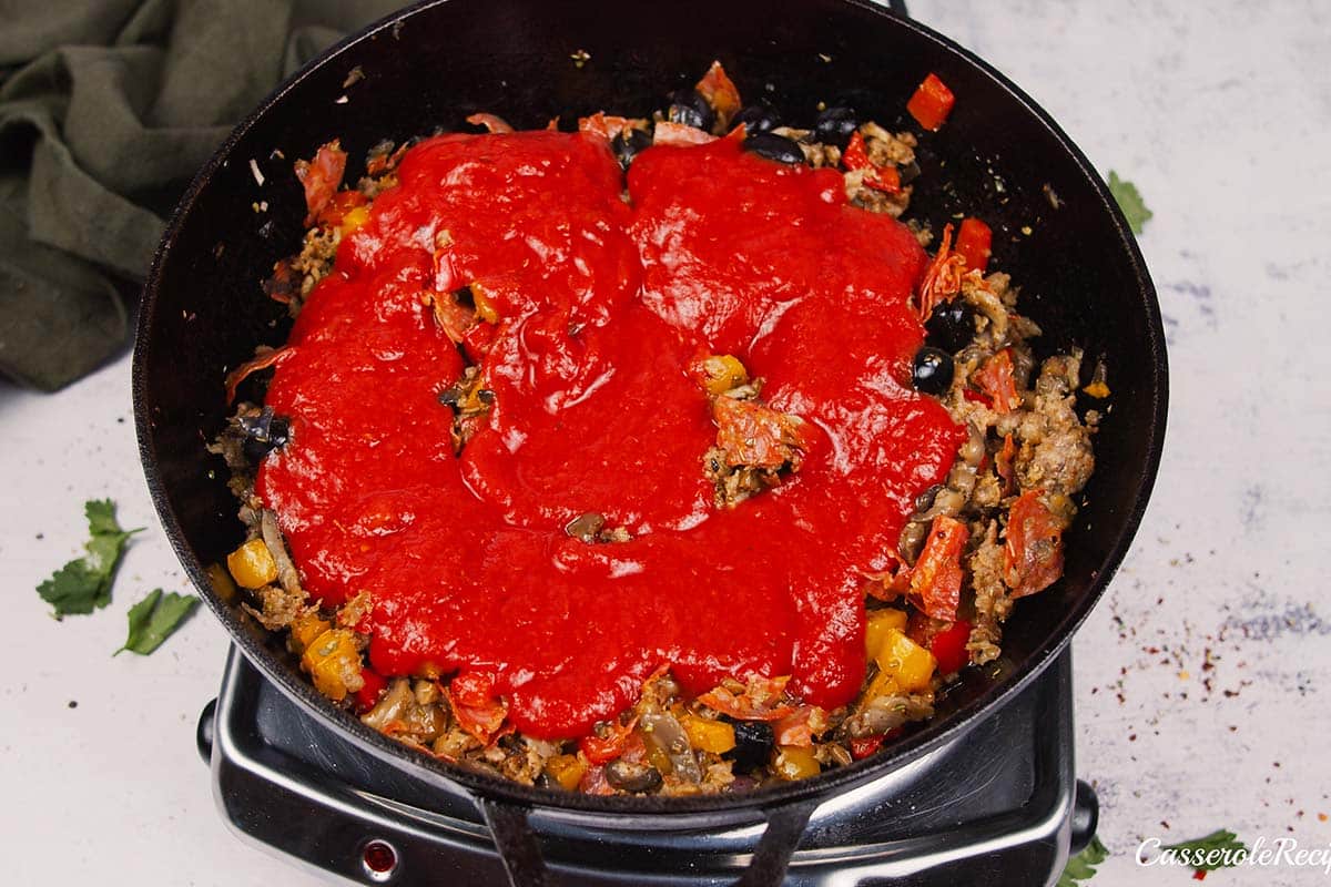 adding tomato sauce to other ingredients to make supreme pizza gnocchi