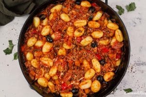 final step of making supreme pizza gnocchi before topping with cheese and baking