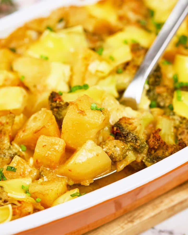 spoon scooping up a serving of vegan potato broccoli casserole from a baking dish