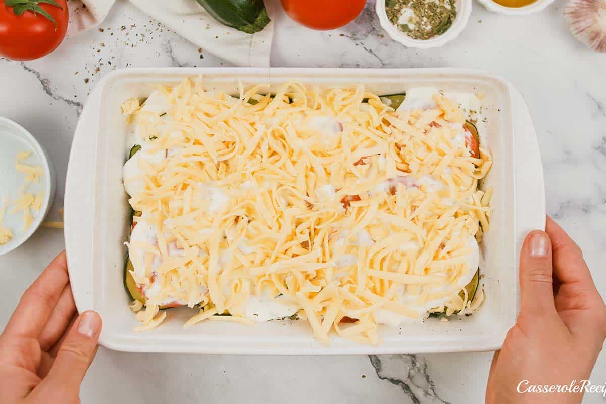 final step of topping the casserole with cheese prior to baking in order to make zucchini tomato casserole
