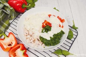 ingredients being combined in a bowl to make the filling for Chicken Caesar Lasagna