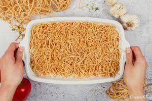 final step of covering a Chicken chow mein casserole with chow mein noodles before baking