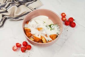 ingredients being combined in a bowl to make alfredo bacon tot casserole