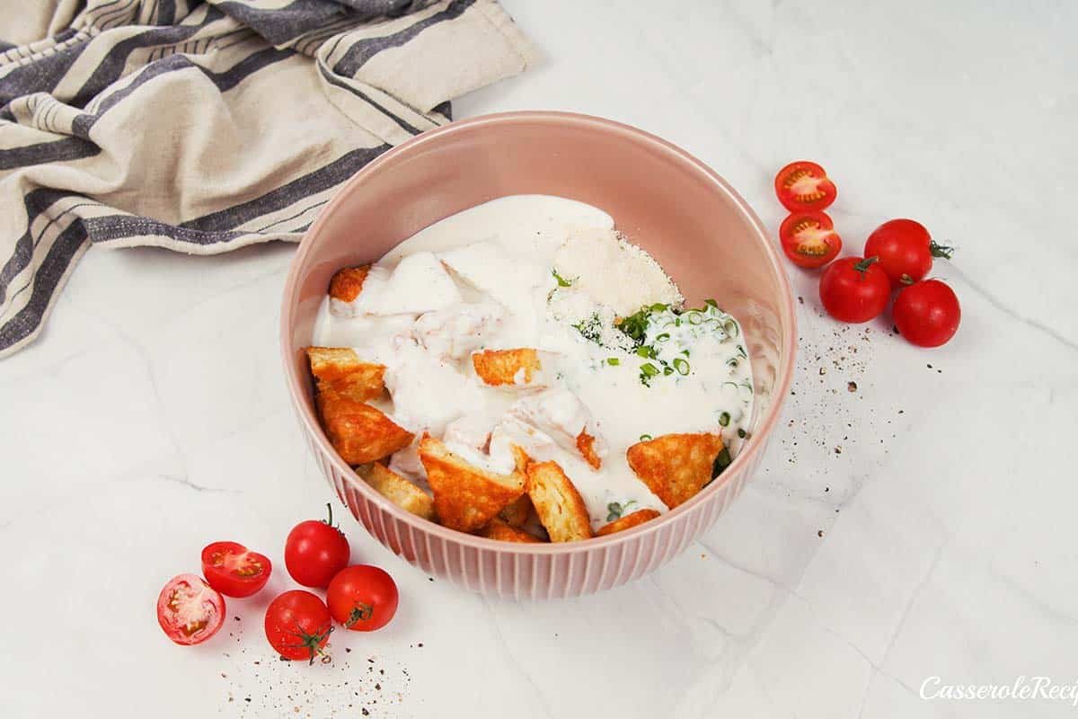 ingredients being combined in a bowl to make alfredo bacon tot casserole