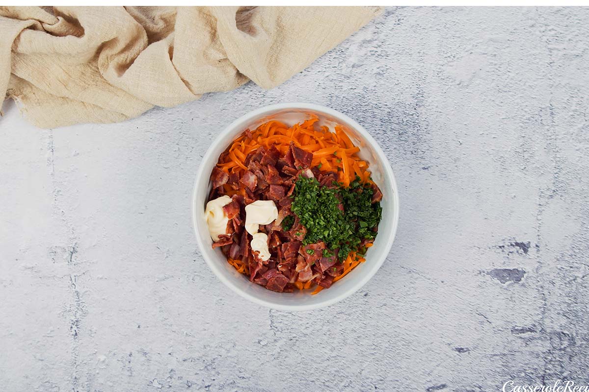 combining ingredients in a bowl to make the filling for bacon grilled cheese sandwich casserole