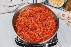 combining tomato sauce and other ingredients in a pot to make baked cavatelli casserole