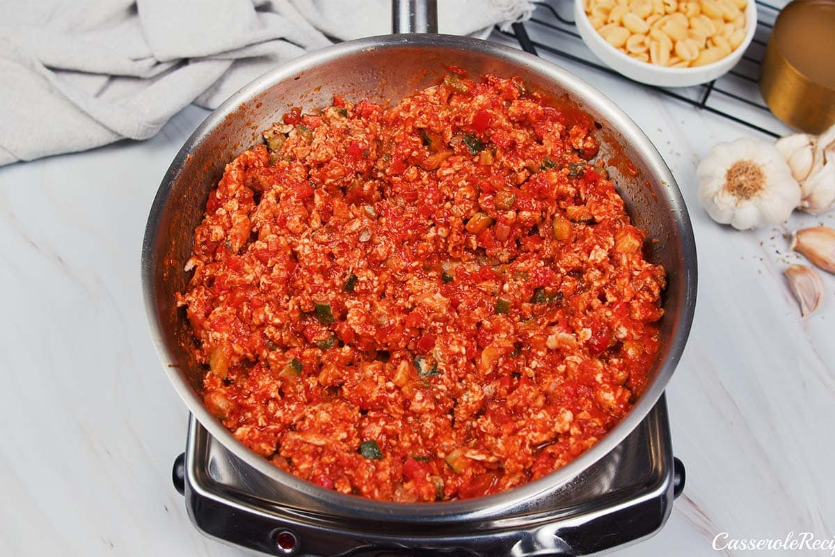 combining tomato sauce and other ingredients in a pot to make baked cavatelli casserole