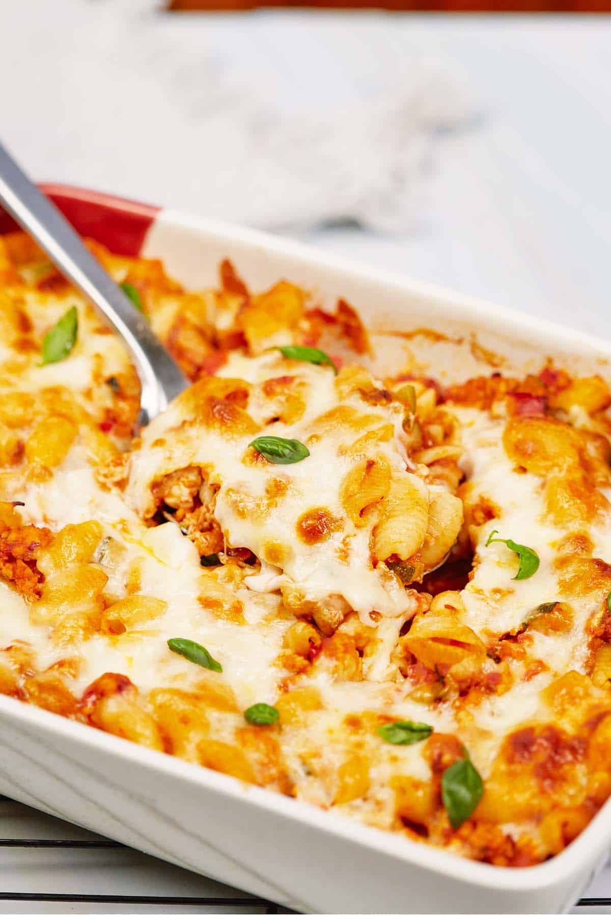 spoon lifting a serving of baked cavatelli casserole from a baking dish