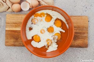adding eggs and cream into a bowl to make baked denver omelette