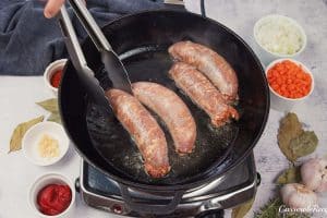 sausages being turned as they cook in a pan to make best ever sausage casserole