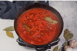 adding basil to the other ingredients in a cast iron dish to make best ever sausage casserole