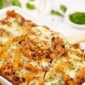 spoon scooping a serving of cheeseburger casserole from a baking dish