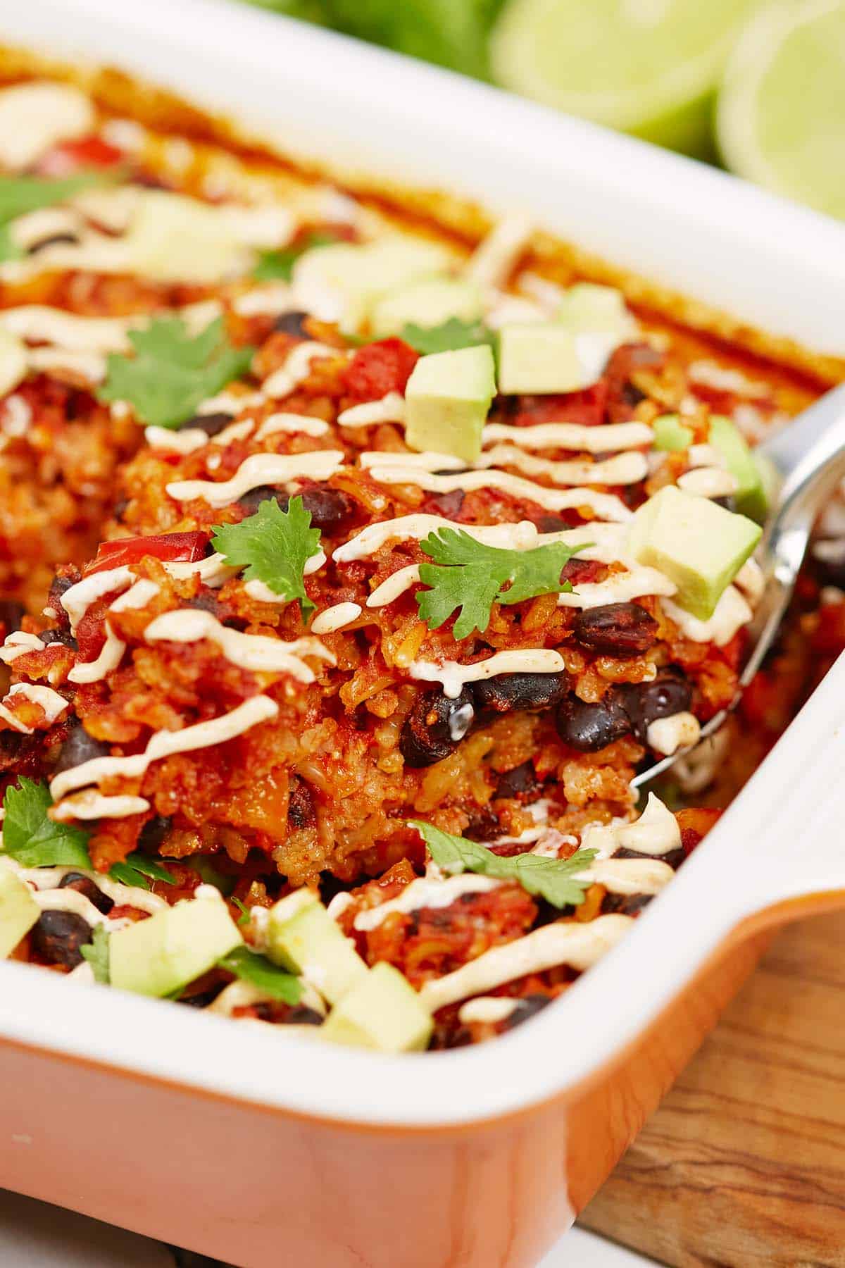 spoon scooping up a serving of chipotle black bean dump and bake casserole from a baking dish