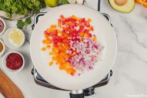 sauteeing onions and other vegetables in a pan to make chipotle black bean dump and bake casserole