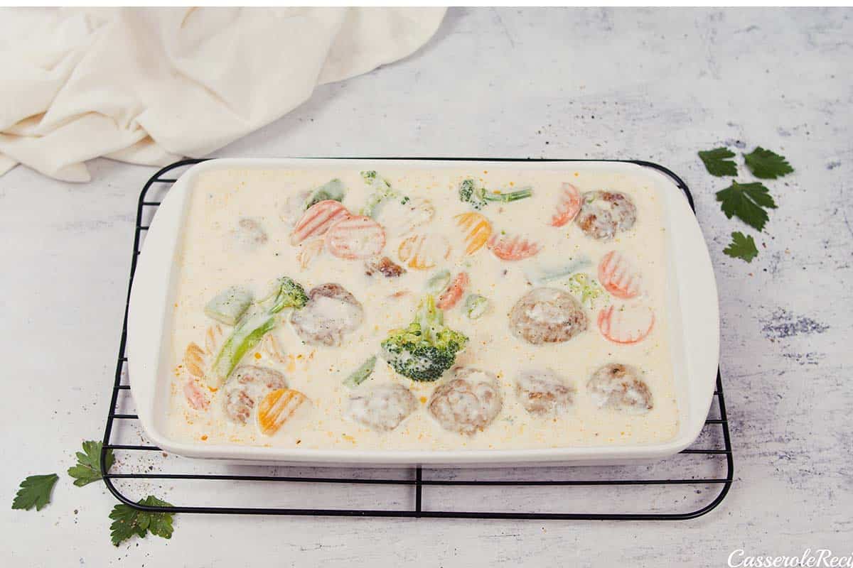 final step of topping creamy meatball casserole with cheese prior to baking