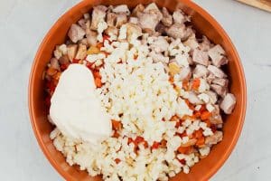 ingredients being combined in a bowl to make the filling to make hot chicken salad bake