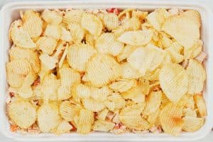 topping a hot chicken salad bake with chips as a final step prior to baking