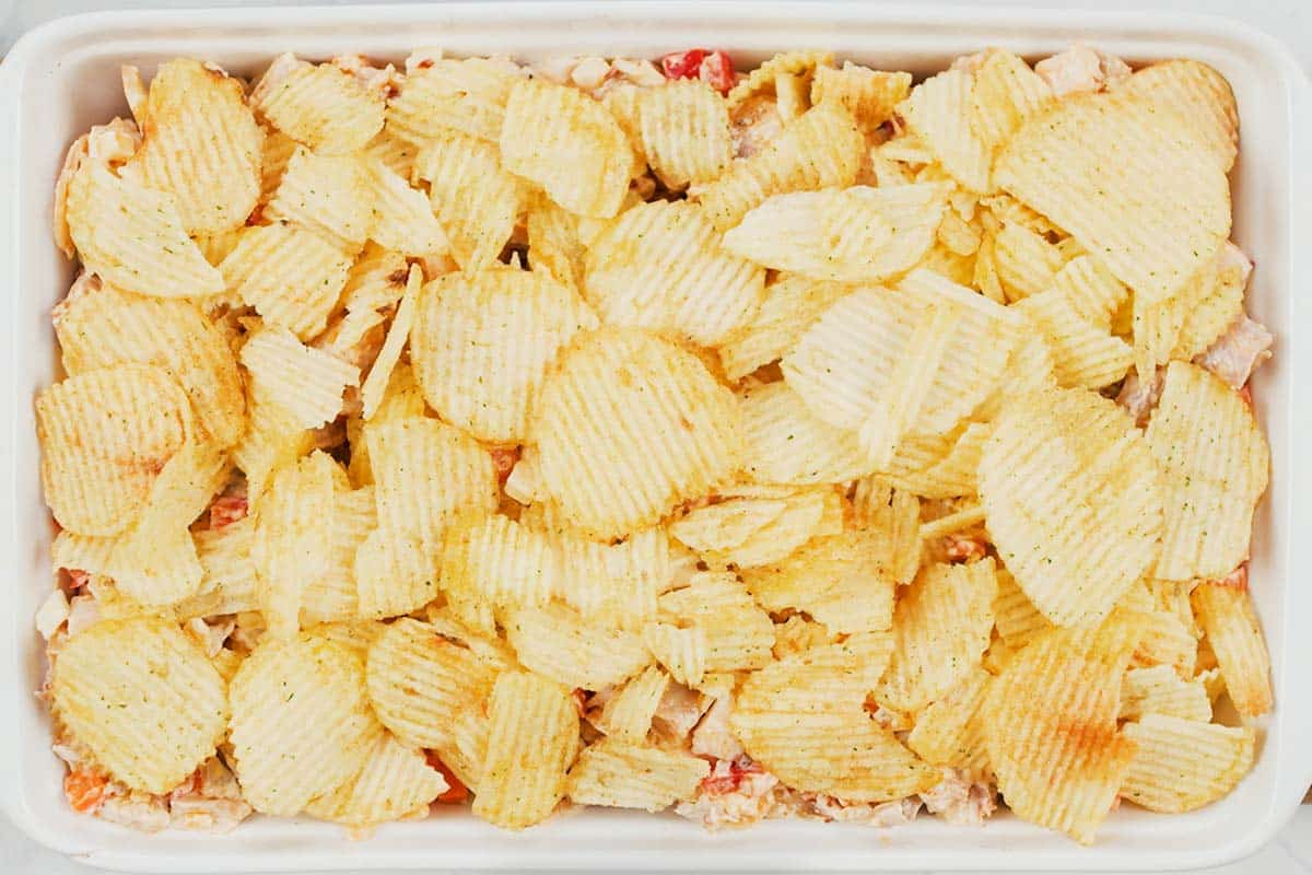 topping a hot chicken salad bake with chips as a final step prior to baking