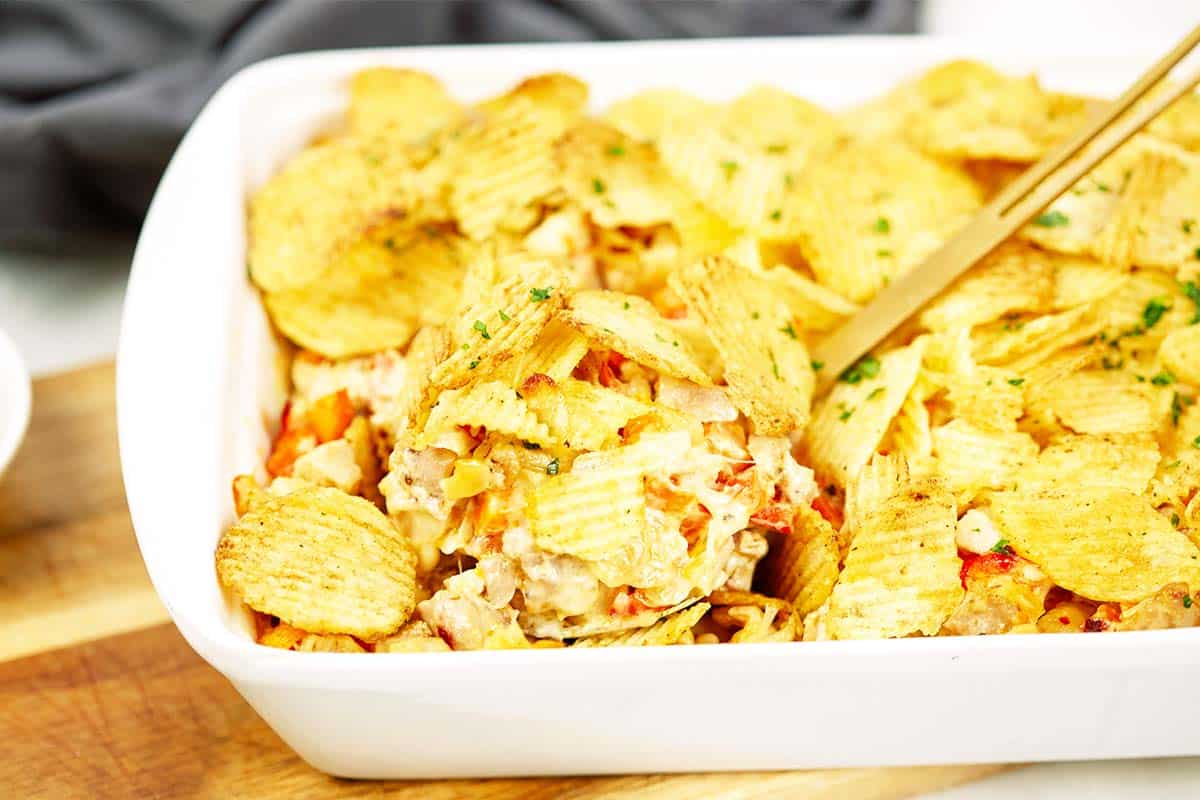 spoon scooping a serving of hot chicken salad bake from a baking dish