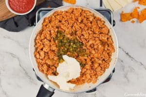 italian sausage and other ingredients being combined to make hot sausage dip