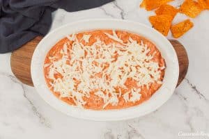 final step of making hot sausage dip by topping with cheese prior to baking