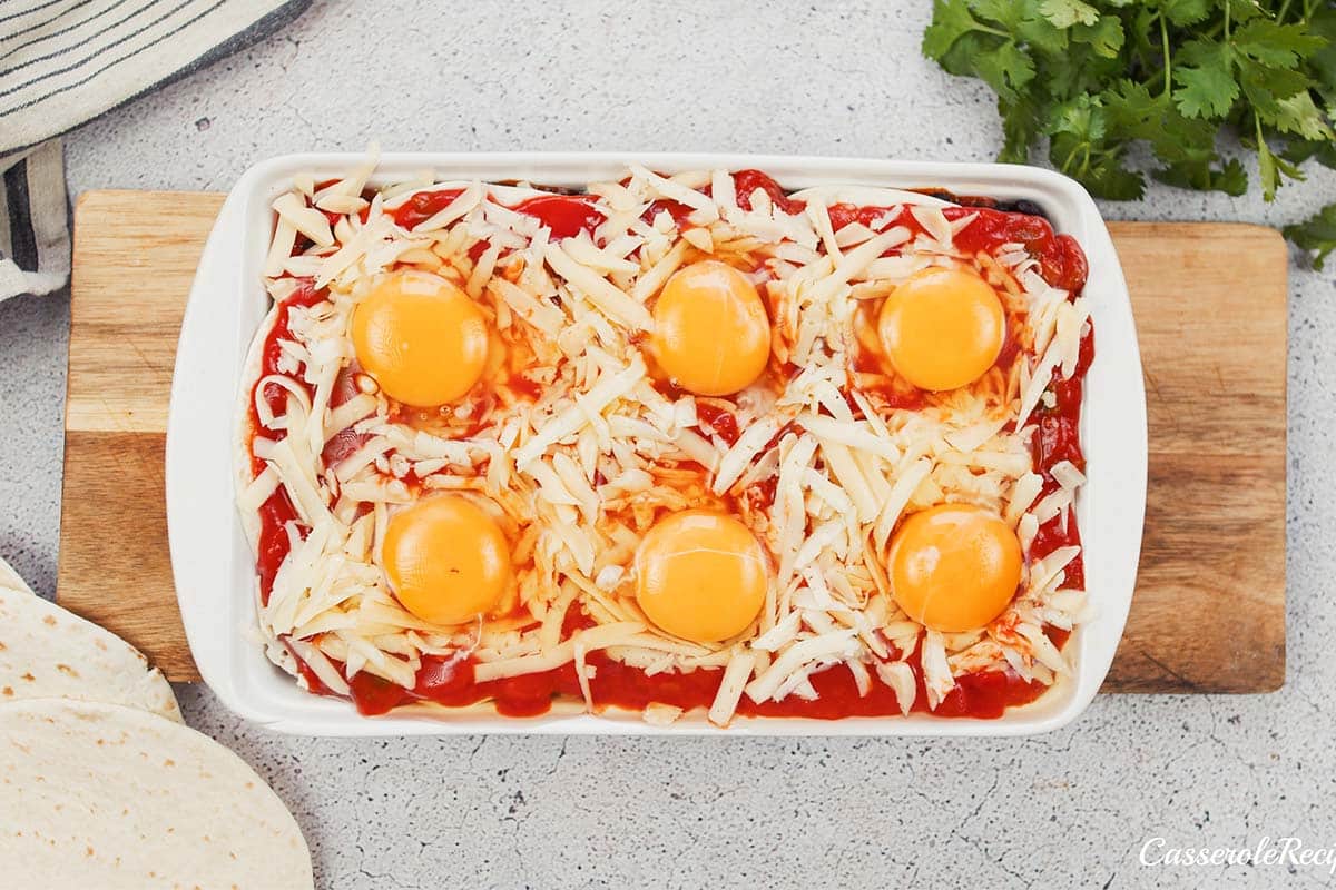 final step of making huevos rancheros casserole by adding the egg on top