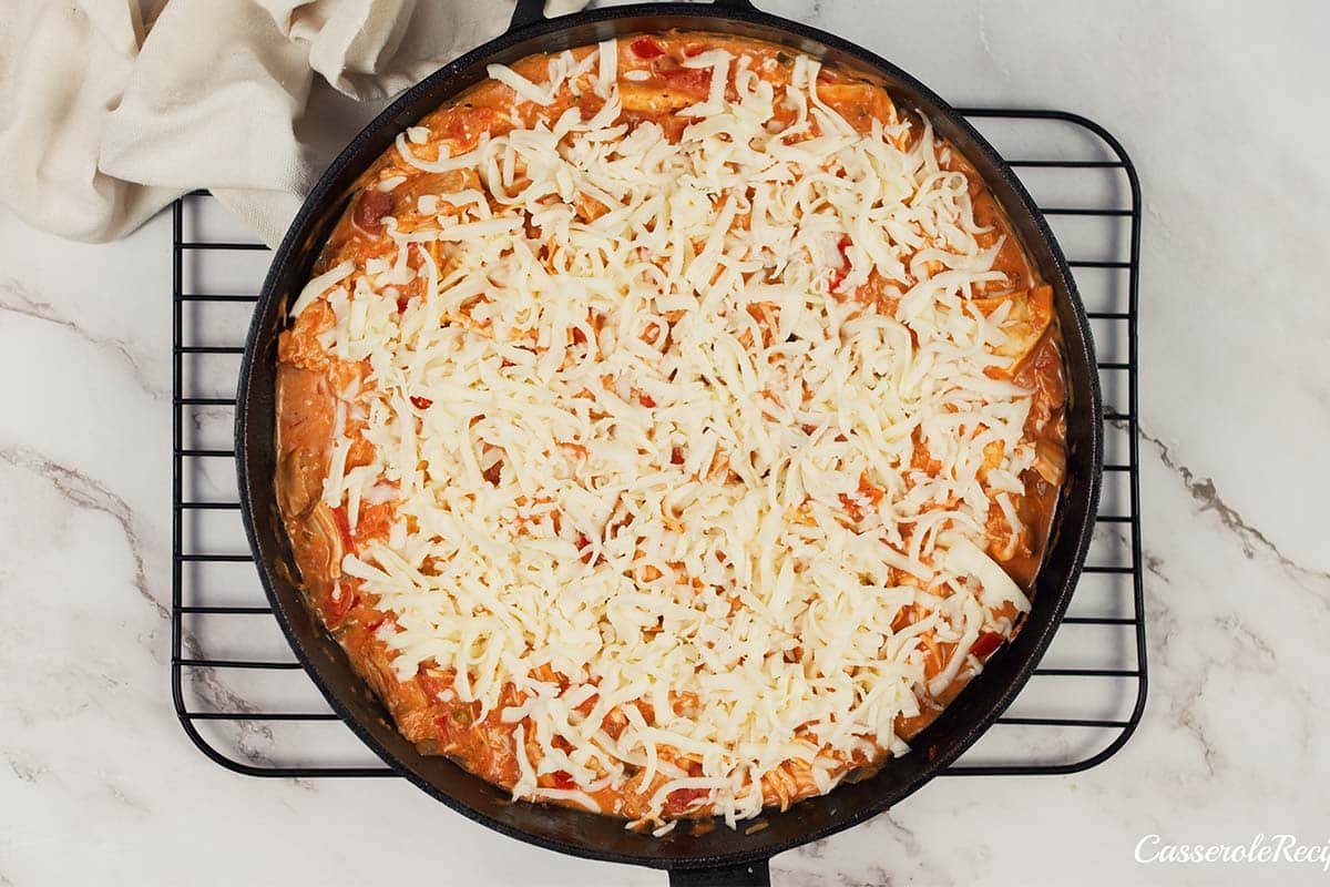 final step of making king ranch chicken casserole by topping it with cheese before baking