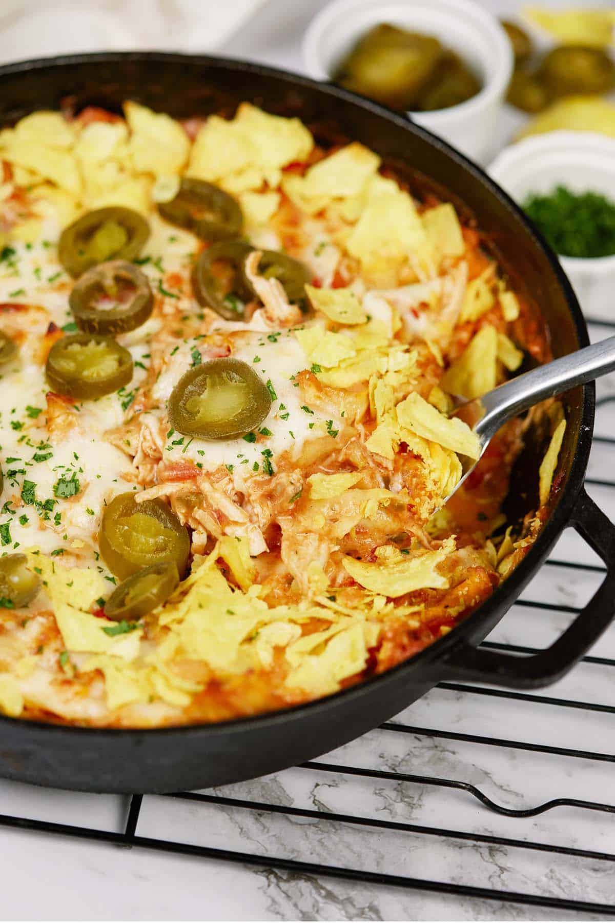 spoon scooping up a serving of king ranch chicken casserole from a cast iron skillet