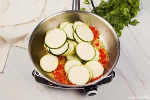 sliced squash being cooked down in a pan with other ingredients to make mini squash casserole
