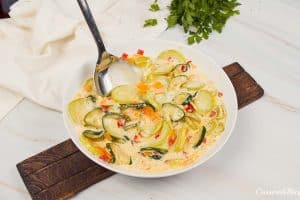 adding ingredients to a baking dish to make mini squash casserole