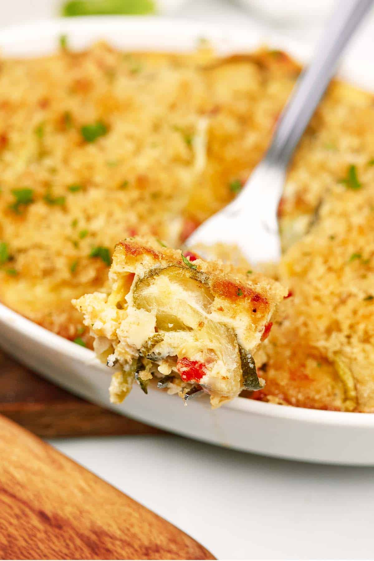 closeup of a fork with a bite of mini squash casserole being held up to enjoy