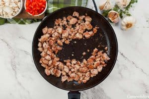 meat being cooked to make noodle pizza casserole