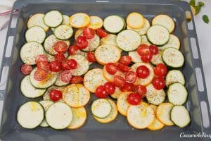 sliced zucchini and other ingredients on a baking pan prepared to be baked to make oven-baked zucchini fritatta