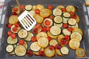 flipping sliced zucchini on a baking pan to make oven-baked zucchini fritatta