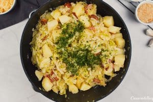 ingredients being sauteed together to make a polish cabbage, potato and bacon casserole