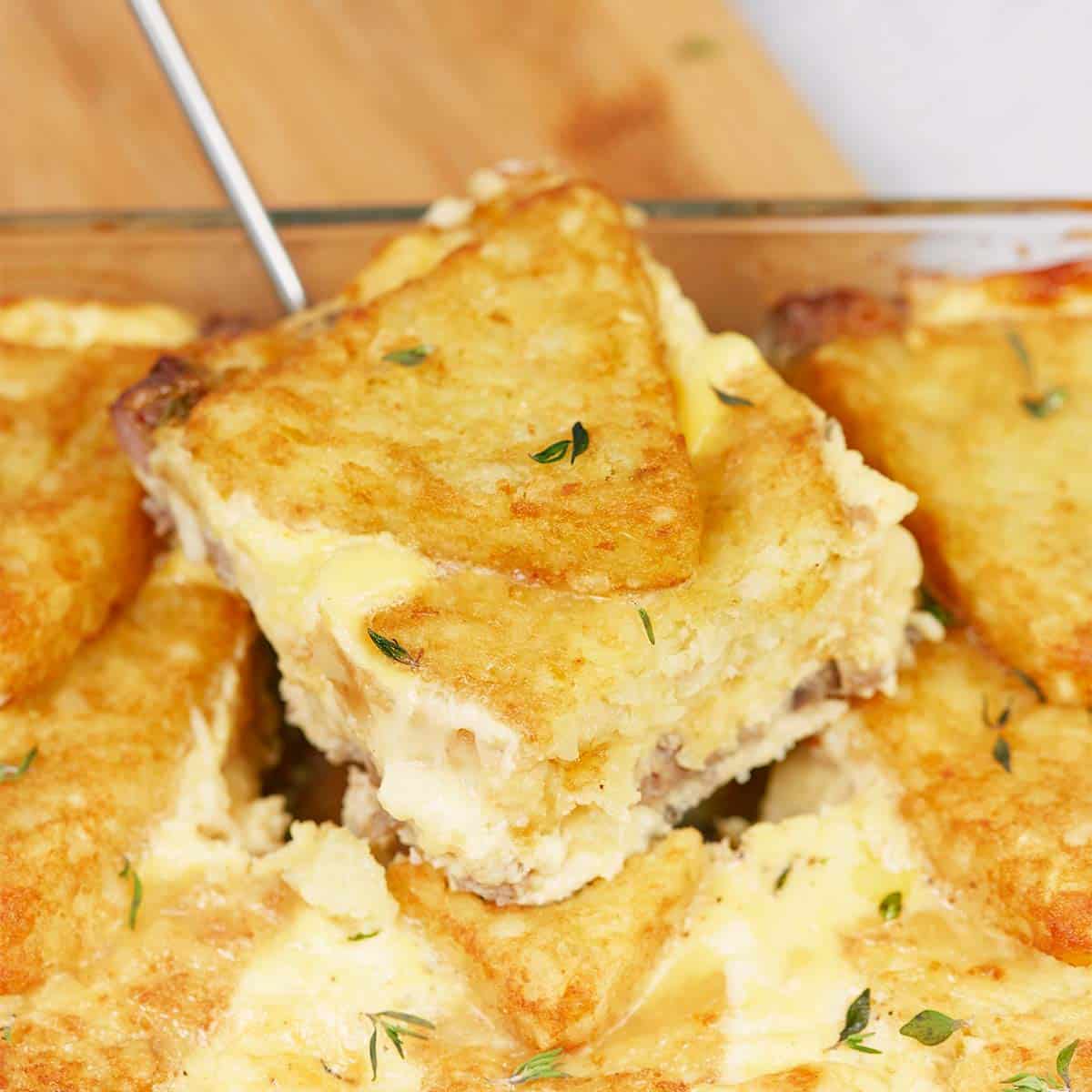 spatula lifting a serving of sausage hashbrown breakfast casserole from a baking dish