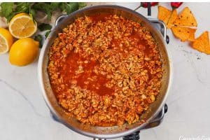 tomato sauce being added to other ingredients in a stock pot to make shawarma casserole