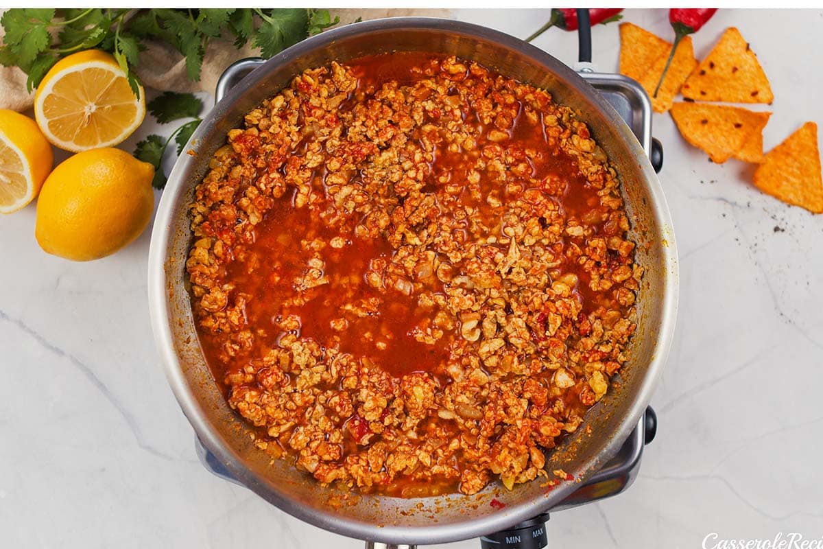 tomato sauce being added to other ingredients in a stock pot to make shawarma casserole