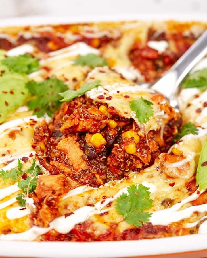 spoon serving a portion of southwest chicken quinoa casserole from a baking dish