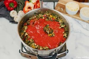 adding ingredients to a dutch oven to make stuffed pepper casserole