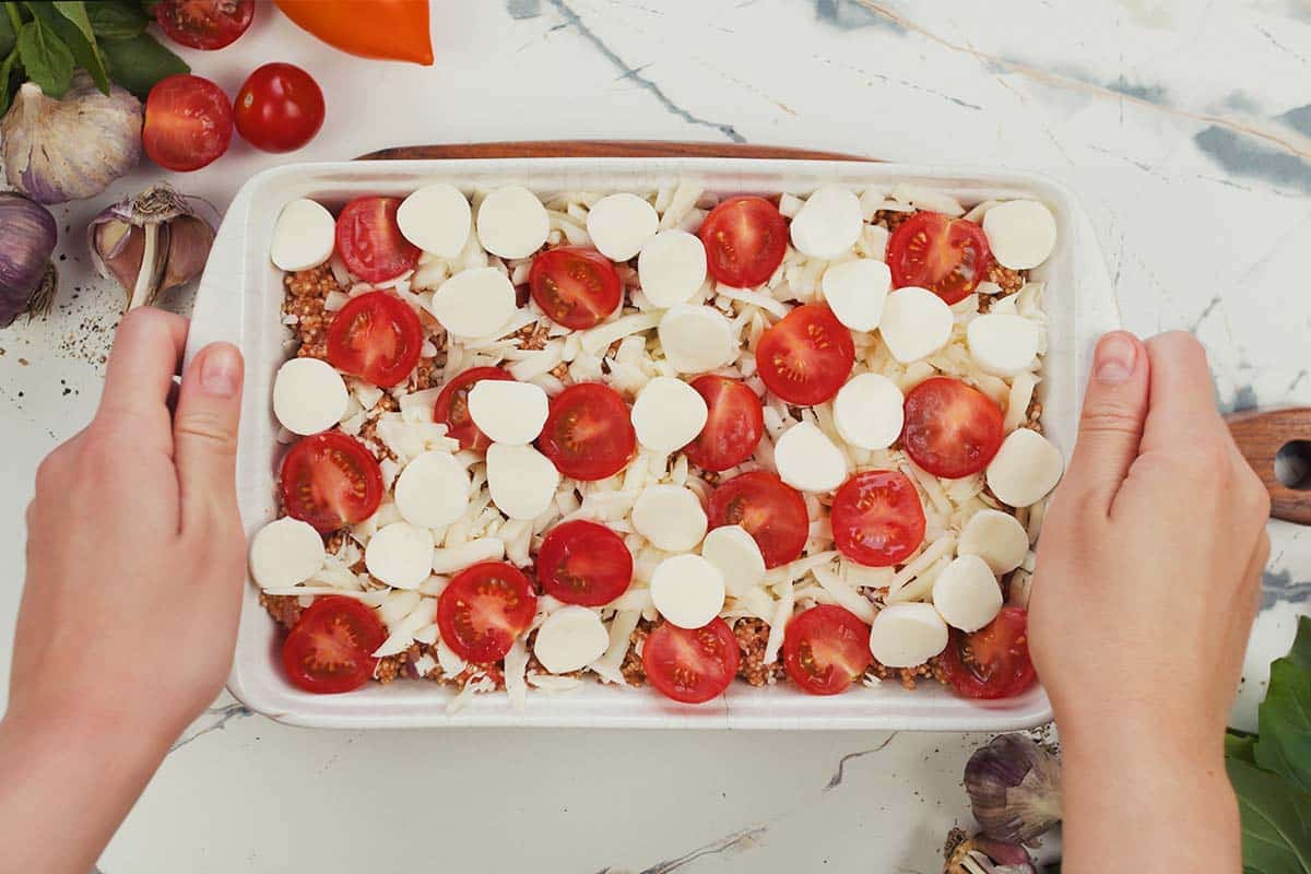 final step of how to make Caprese Quinoa Bake by topping with mozzarella cheese balls prior to baking