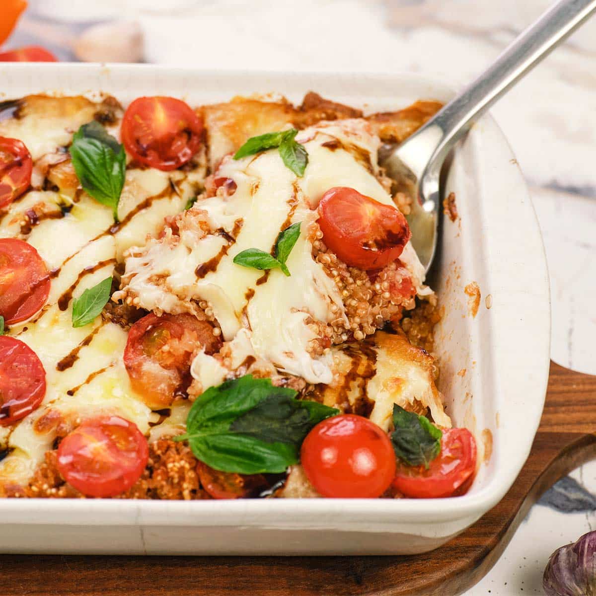 spoon scooping up a serving of Caprese Quinoa Bake from a baking dish