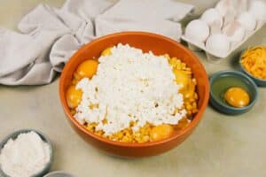 cottage cheese being added to corn and other ingredients to make Corn and Cheese Pashtida Crustless Corn Quiche