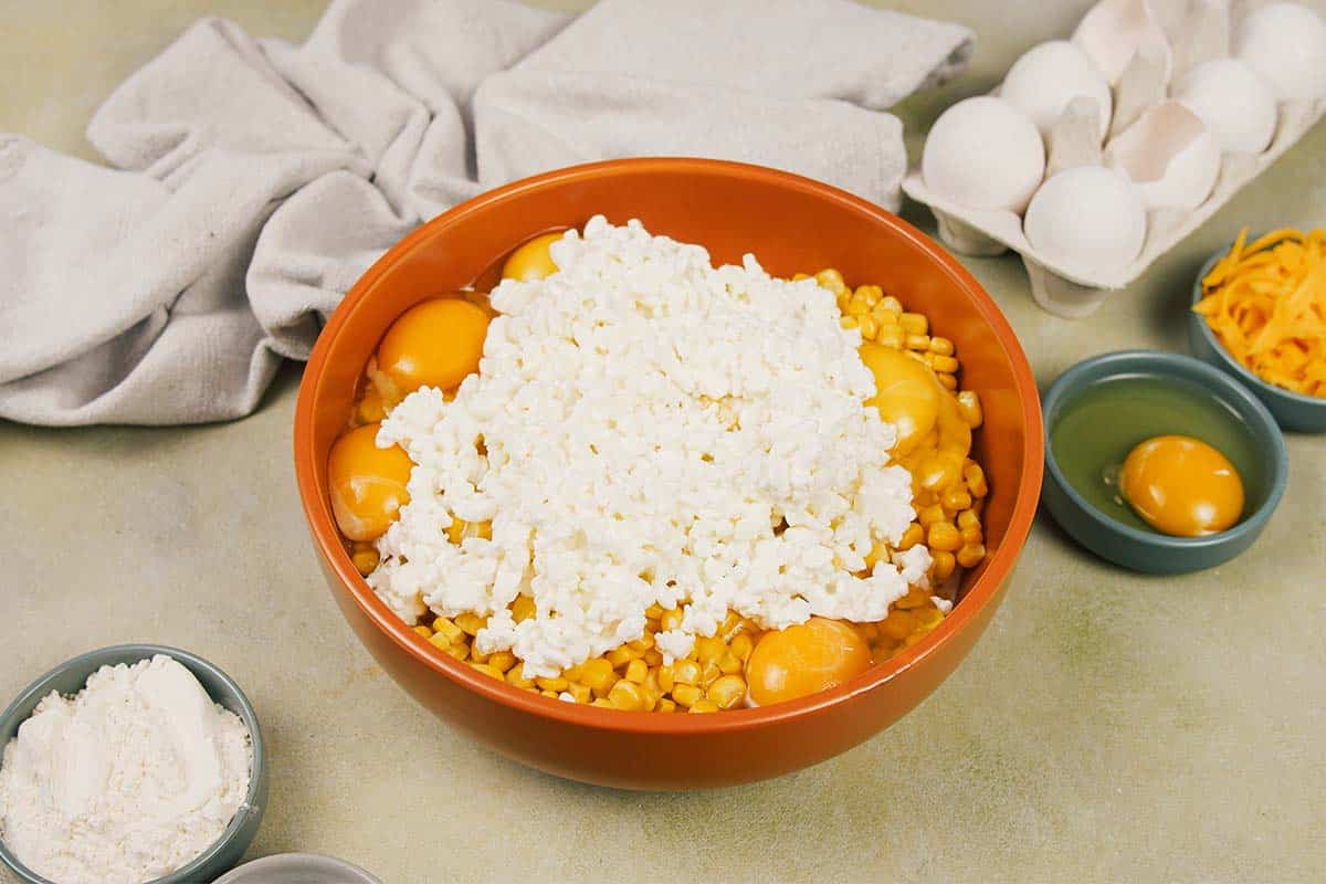 cottage cheese being added to corn and other ingredients to make Corn and Cheese Pashtida Crustless Corn Quiche