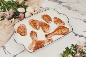 final step of making Creamy Orzo Chicken Bake by coving the chicken with sauce before baking