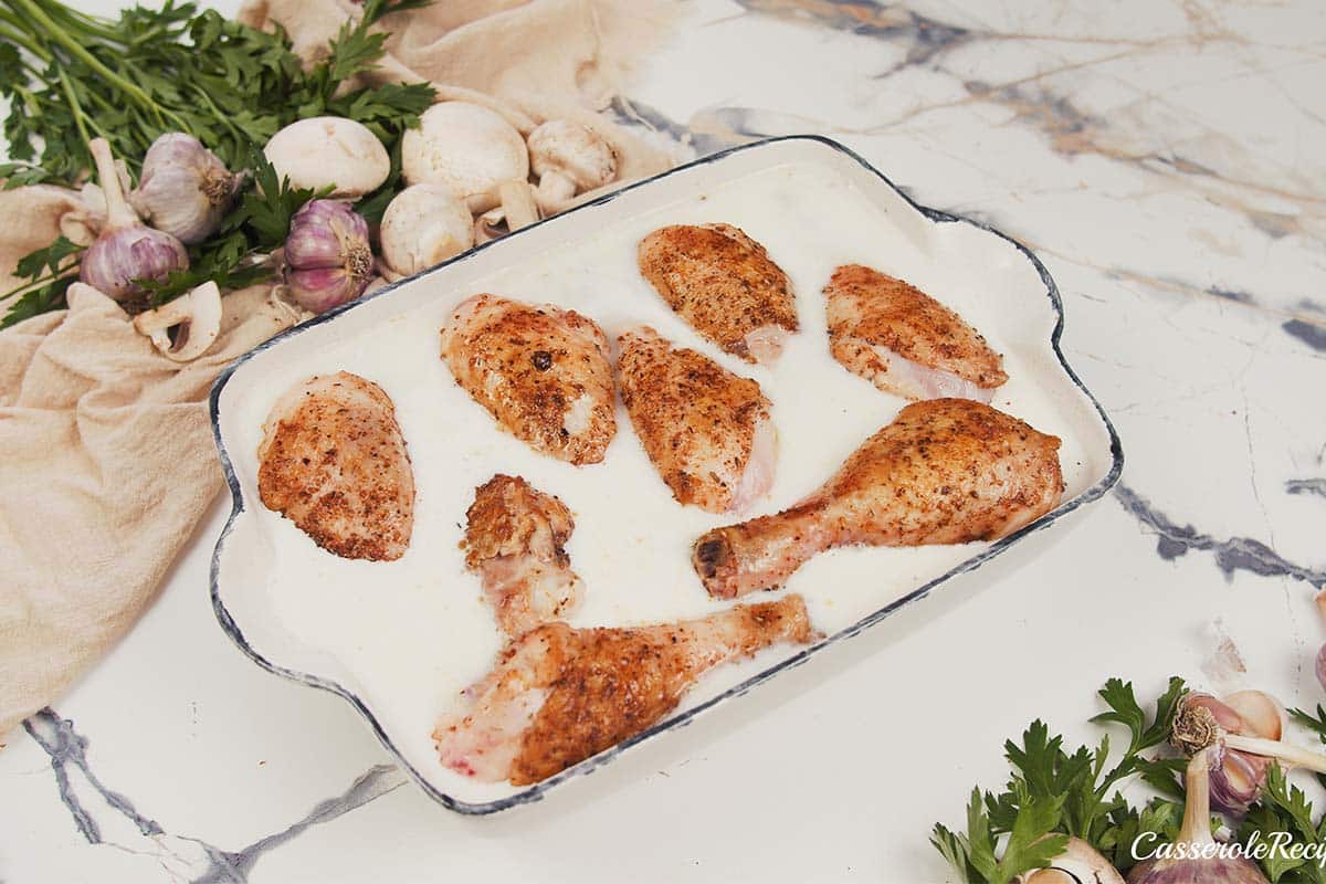 final step of making Creamy Orzo Chicken Bake by coving the chicken with sauce before baking