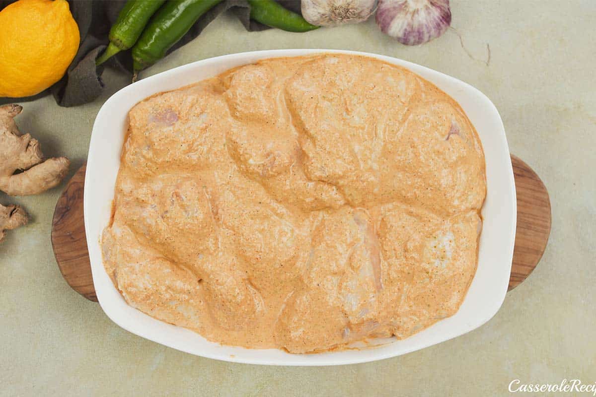final step of transferring the prepared chicken to a baking dish to make Mum's curried Chicken Bake (tandoori chicken curry)