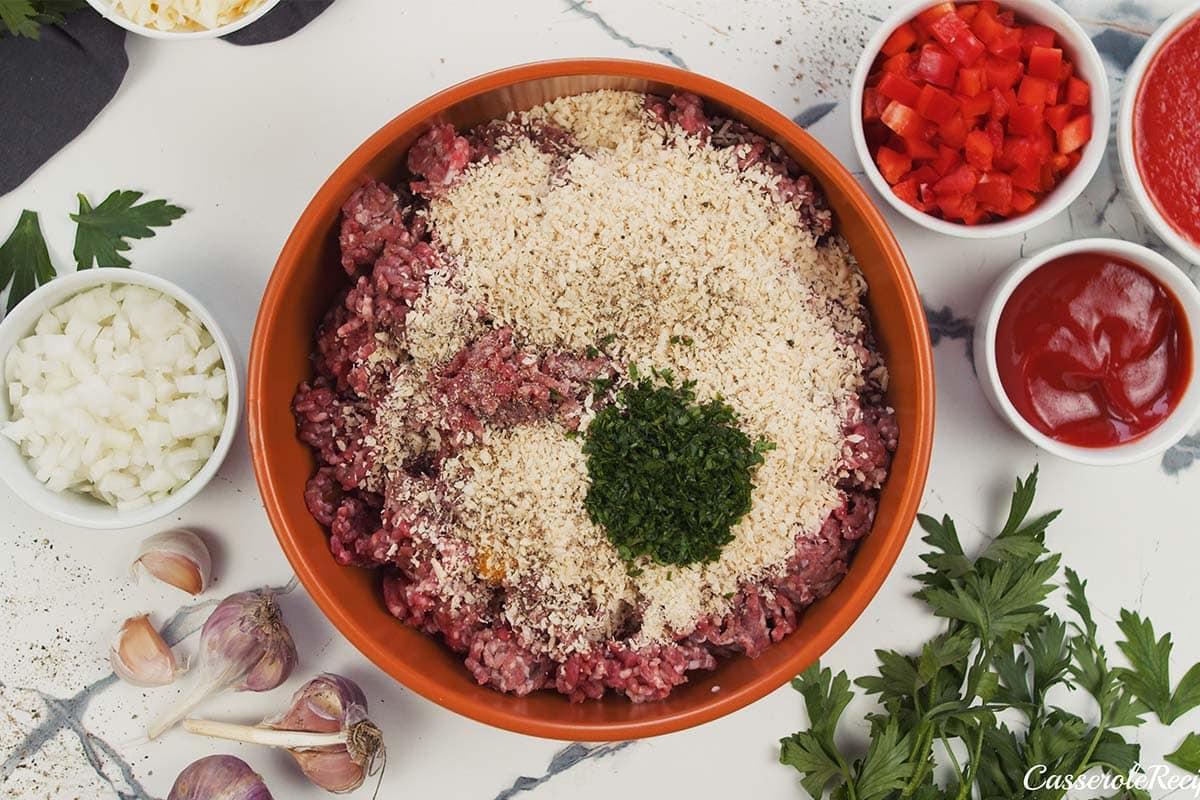 meat and other ingredients being combined in a bowl to make meatballs for Sloppy Joe Meatball Bake