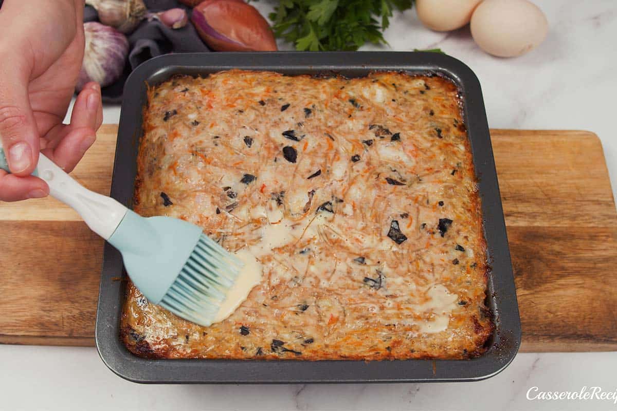 brushing egg on top of Vietnamese Pork Bake to crisp the top